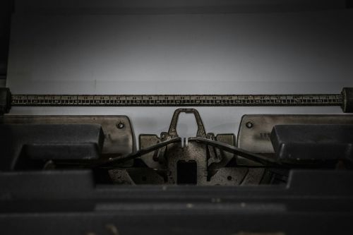Close-up of a vintage typewriter with blank paper, showcasing retro technology.